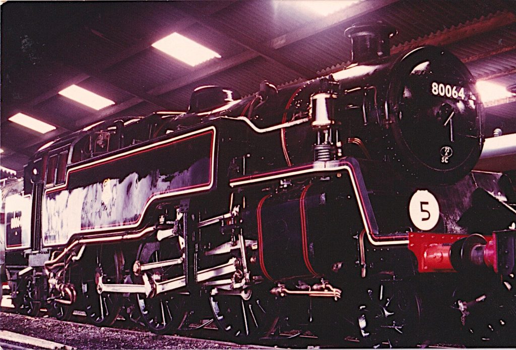 Close view of 80064 inside an engine shed, its fresh paint and red and cream lining shining under the lights.