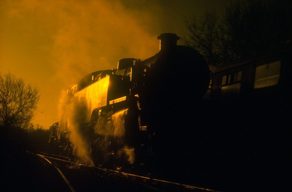 The front of 80064 in shadow, steam lit gold by the setting sun.
